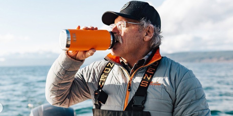 man drinking from orange yeti bottle