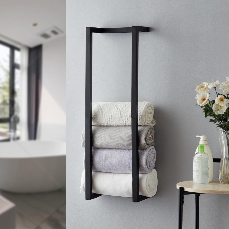 black metal towel rack on wall in bathroom with rolled towels inside