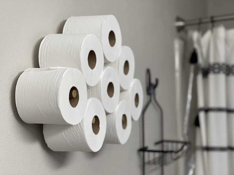 close up of toilet paper hanging on wall pegs in bathroom