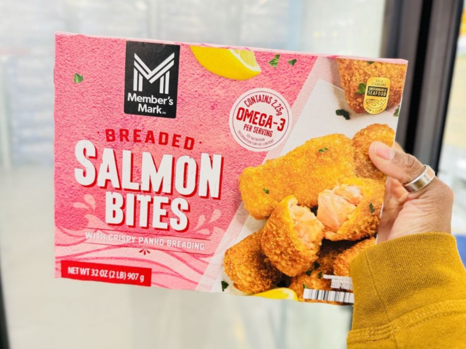 a womans hand holding a box of salmon biites