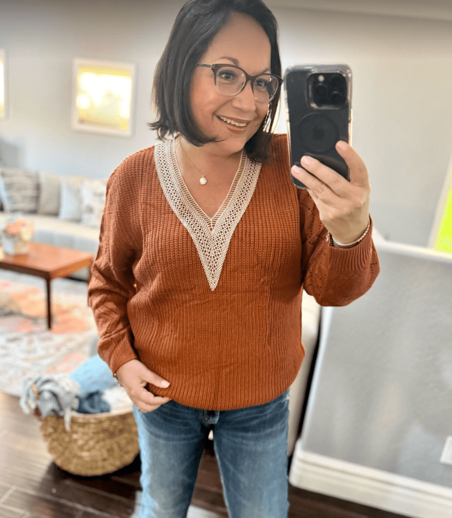 woman in orange sweater taking selfie