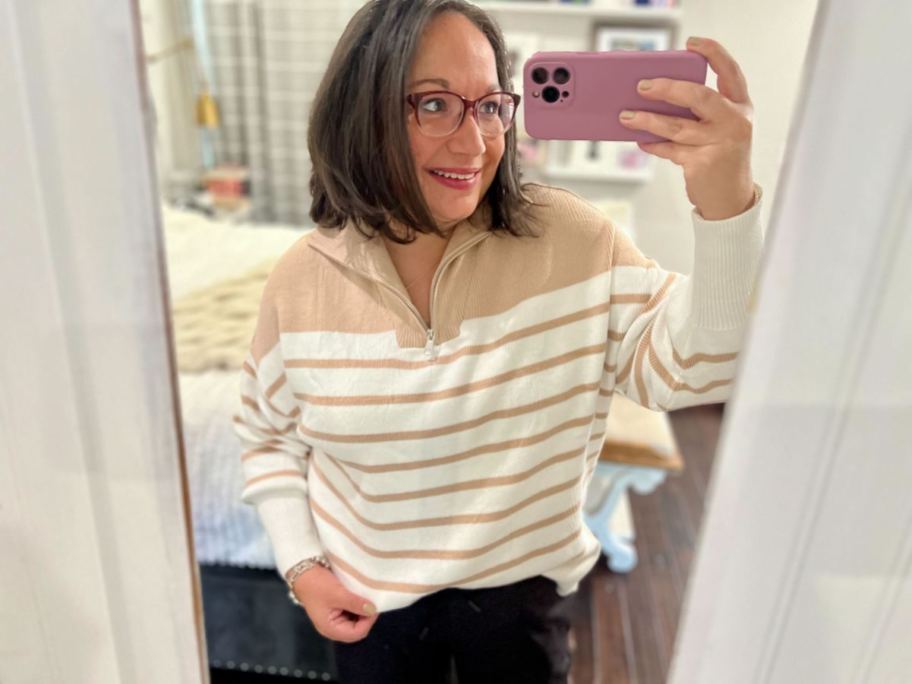 woman taking mirror selfie with beige and white sweater