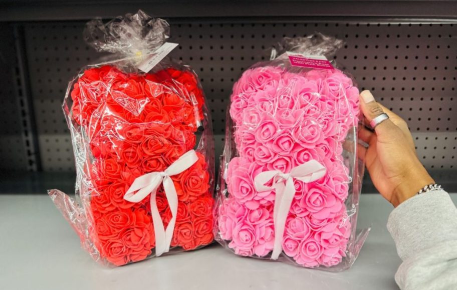 womans hand reaching for a pink bear on a store shelf sitting next to a red bear