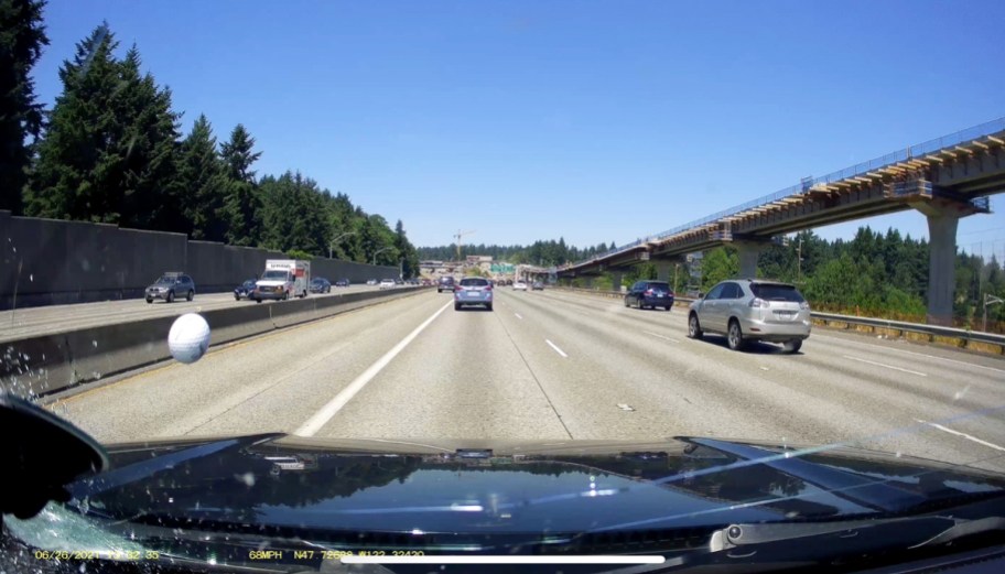 footage of golf ball hitting car on highway from dash cam