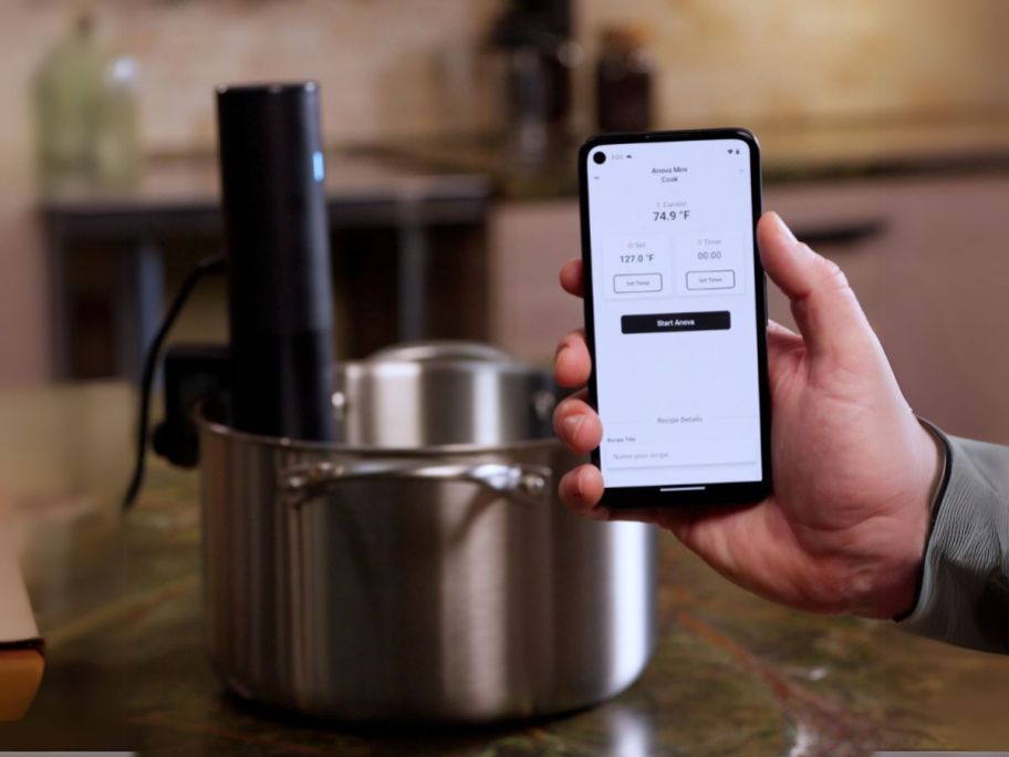 person holding phone using Anova app to monitor cooking