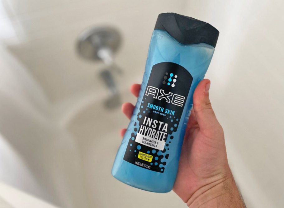 man holding blue and black bottle of axe body wash in shower