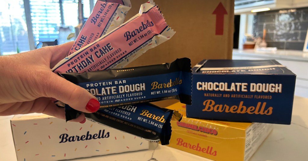 person holding up birthday cake and chocolate dough barebells protein bars