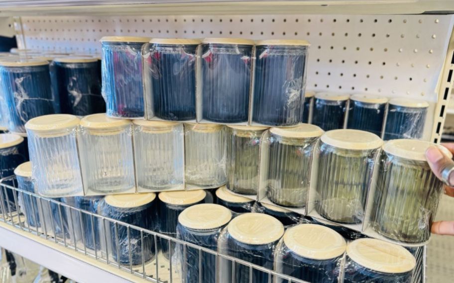 a womans hand holding a 4 pack of glass storage jars