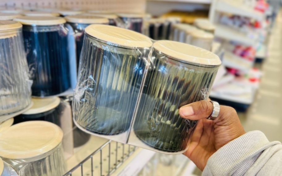 a womans hand holding a 2 pack of glass storage jars