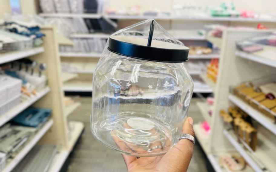 womans hand holding a large glass jar