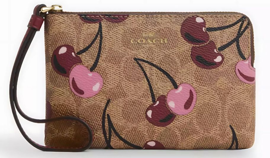 A tan Coach Wristlet with cherries on it 