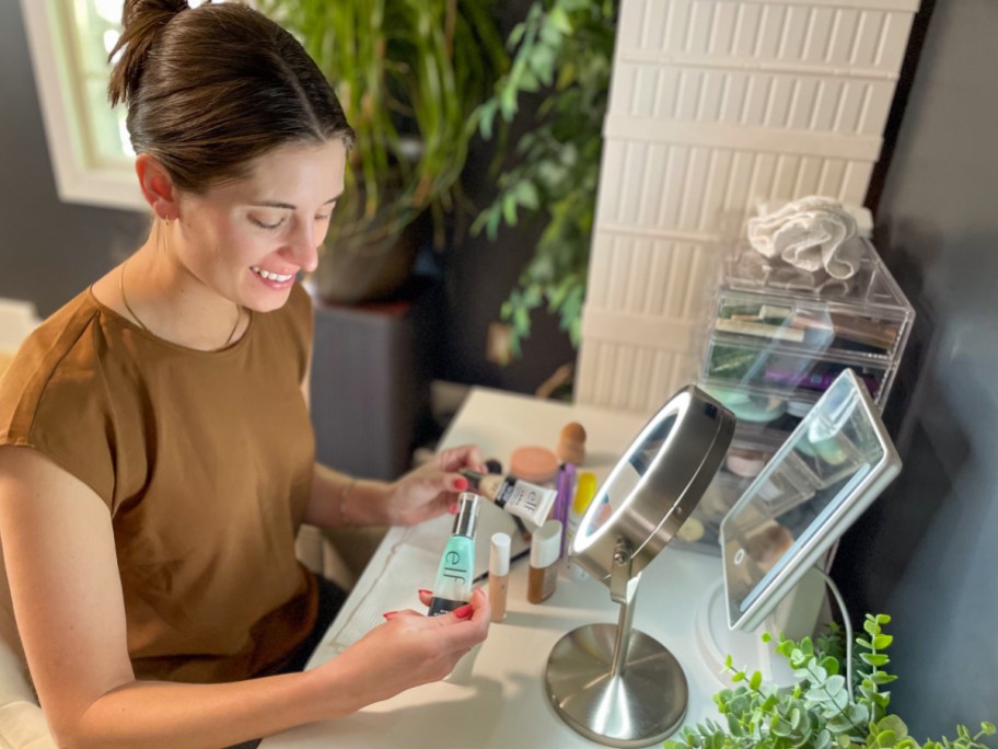 Woman sitting at a vanity table using e.l.f. cosmetics makeup products and beauty tools