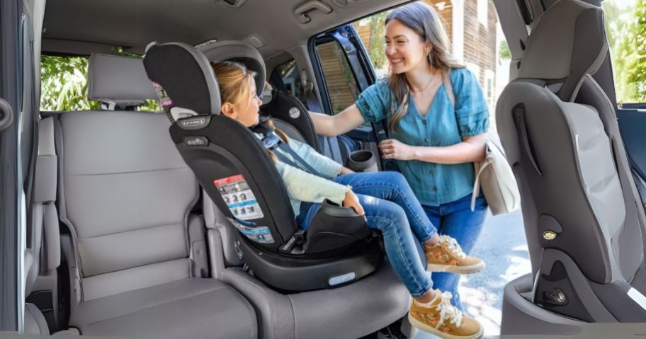 woman helping child in Evenflo Revolve 360 Extend All-in-One Rotational Convertible Car Seat w/ Quick Clean Cover in van