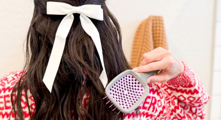 Woman using unbrush on her hair with a bow