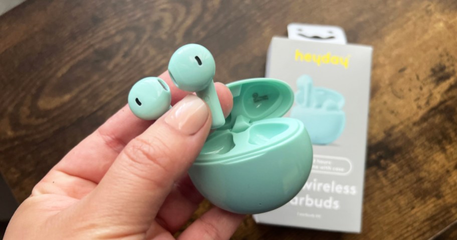 hand holding a teal set of heyday Bluetooth Wireless Earbuds with their box in the background