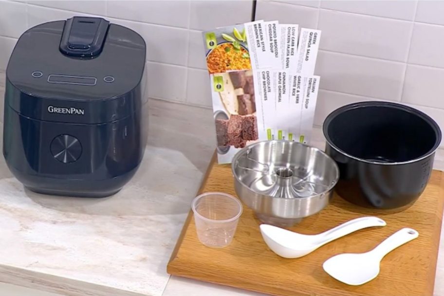 A GreenPan Rice Cooker next to a cutting board with accessories and recipe cards