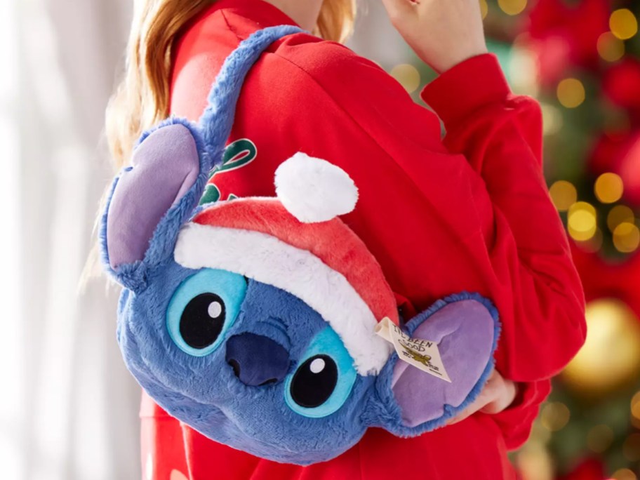 woman in red sweater with plush santa stitch shoulder bag