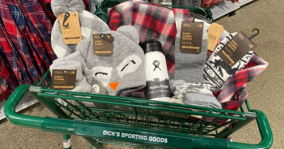 A Dick's Sporting Goods Shopping Cart filled with Cozy Cabin socks, hats, slippers and blanket