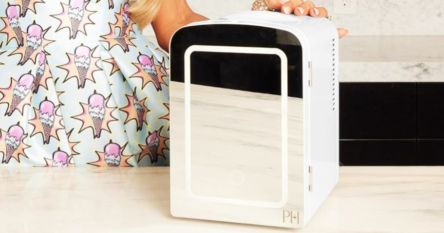 woman touching mirrored mini fridge on table