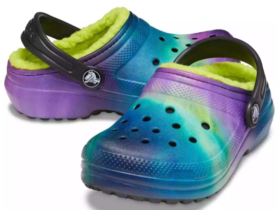 a pair of kids crocs in a multicolor pattern with purples, blues, greens, and yellows