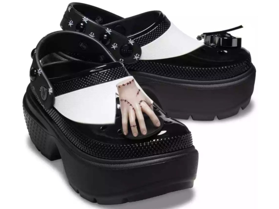 a pair of black and white platform Crocs shoes that look like Wednesday Addam's shoes with a small hand on the foot to represent Thing from the Addams Family