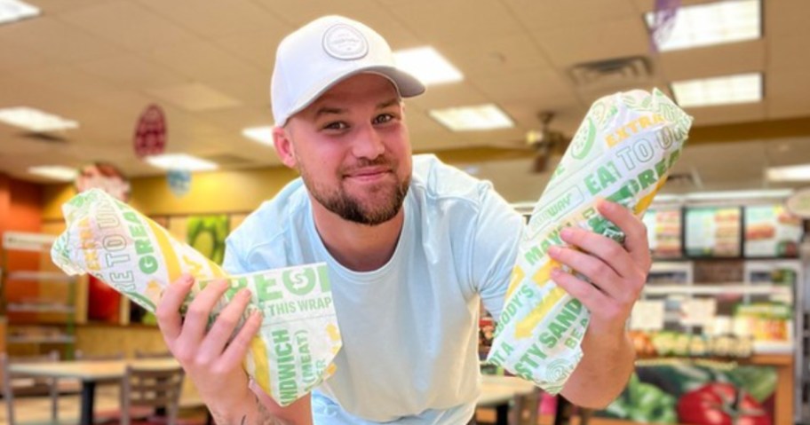 Happy guy holding two Subway footlongs