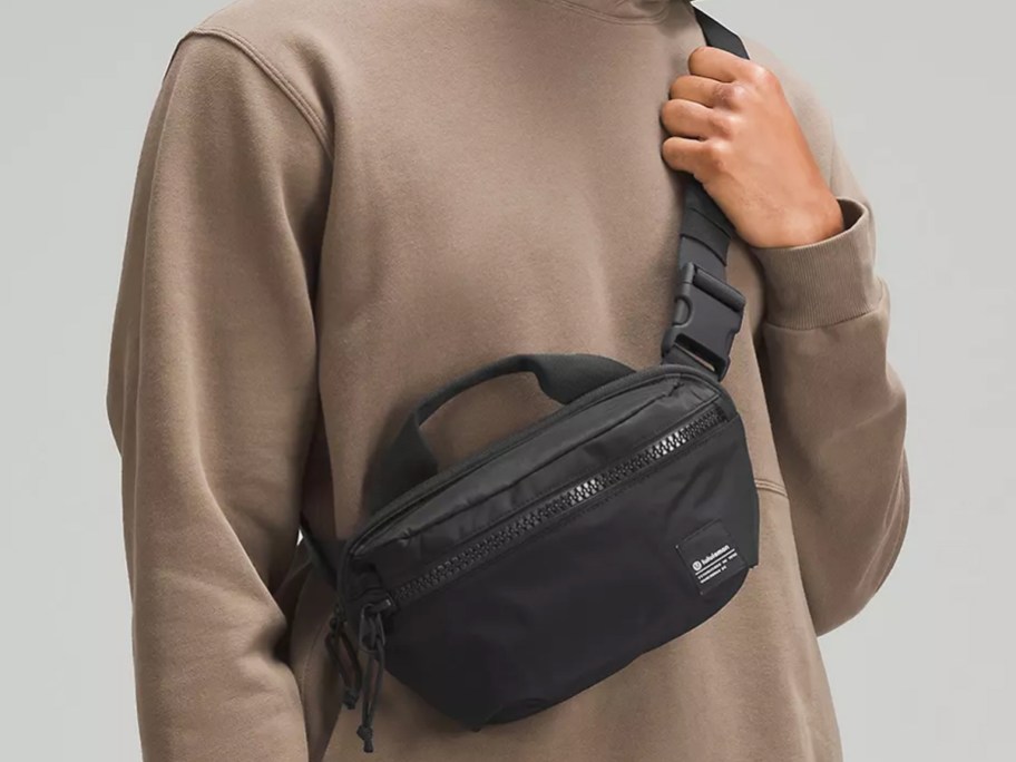 man in brown hoodie with a black belt bag across chest