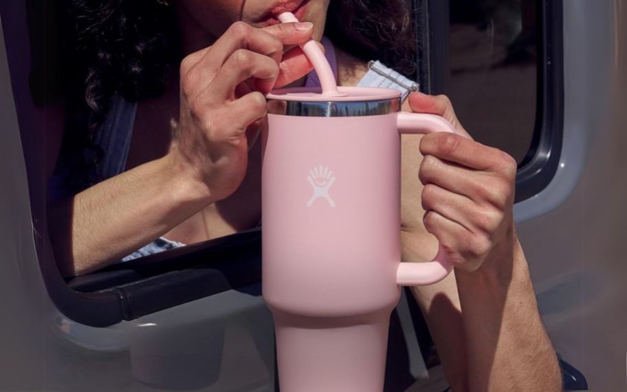 a woman drinking from a pink hydroflask tumbler