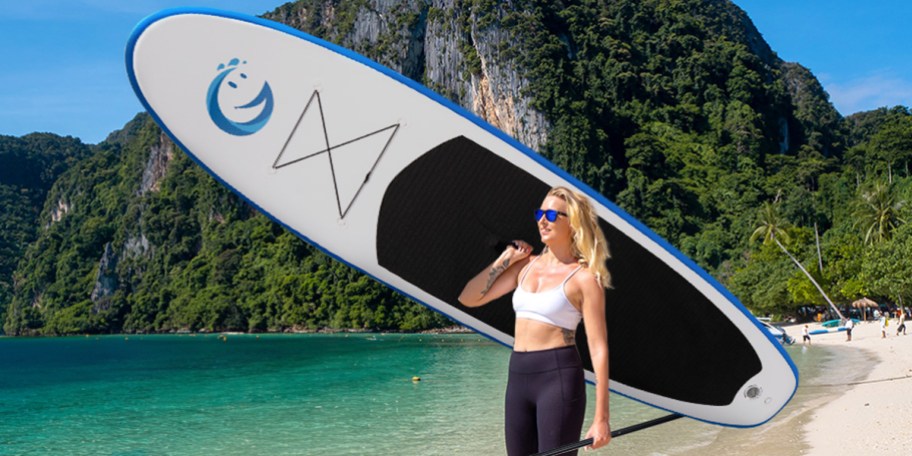 woman holding white and blue paddleboard 