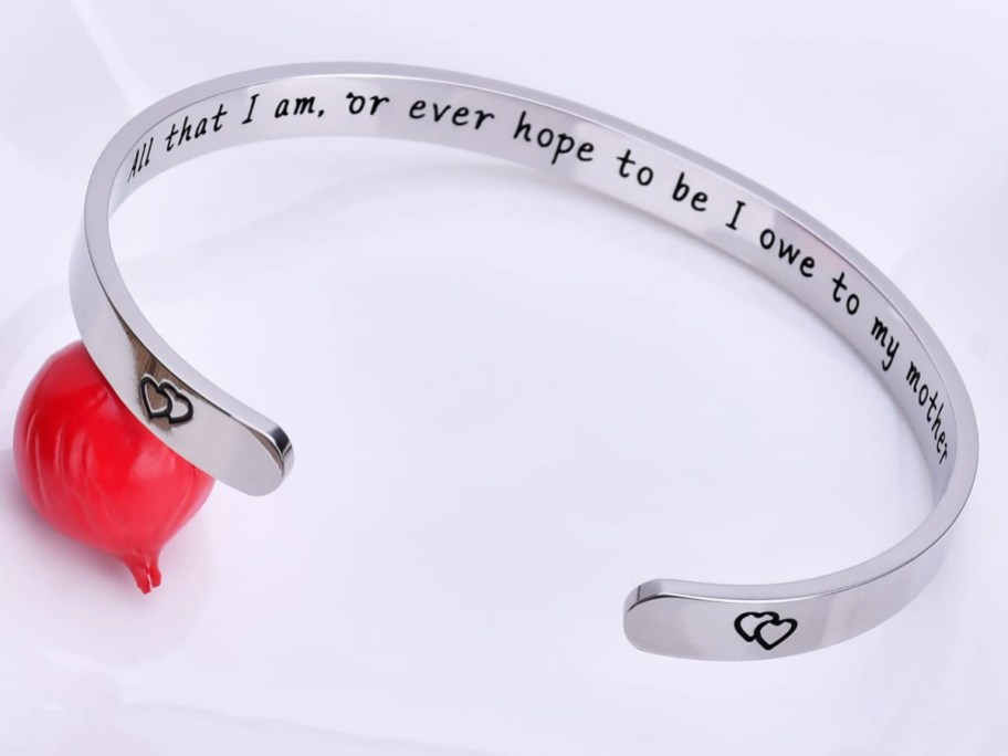 silver cuff bracelet that says "All that I am, or ever hope to be I owe to my mother" on the inside