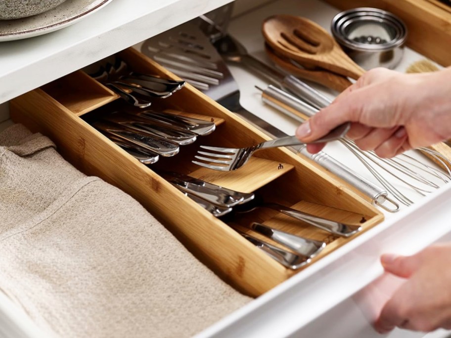 hand grabbing fork from bamboo organizer inside drawer