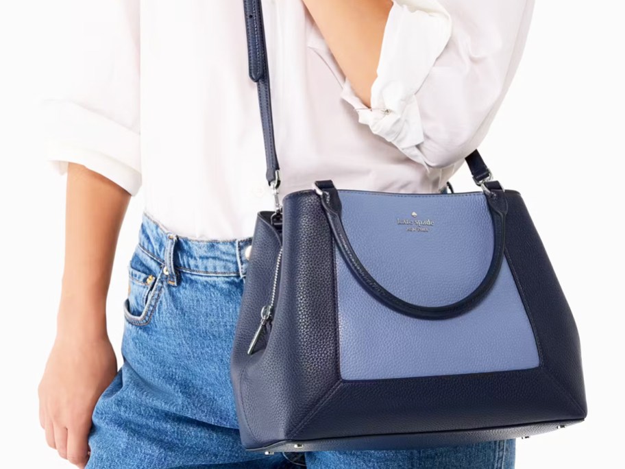 woman in a white top and jeans with a blue colorblock purse