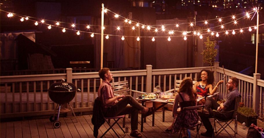 People sitting outside at a table with LED string lights hanging overhead