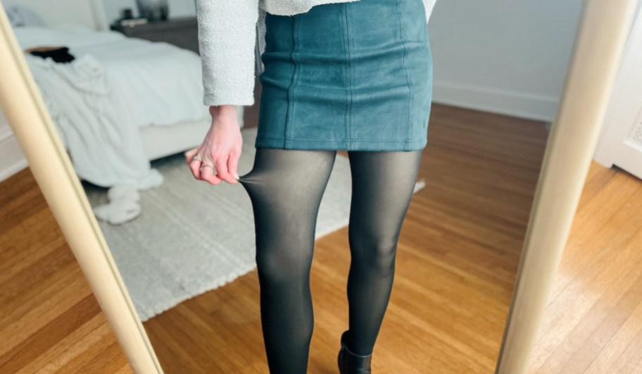 woman pulling side of fleece lined tights in mirror