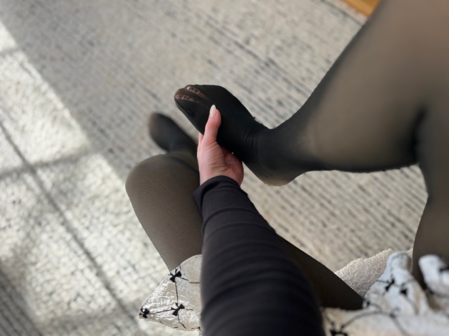 hand holding foot with run in black tights