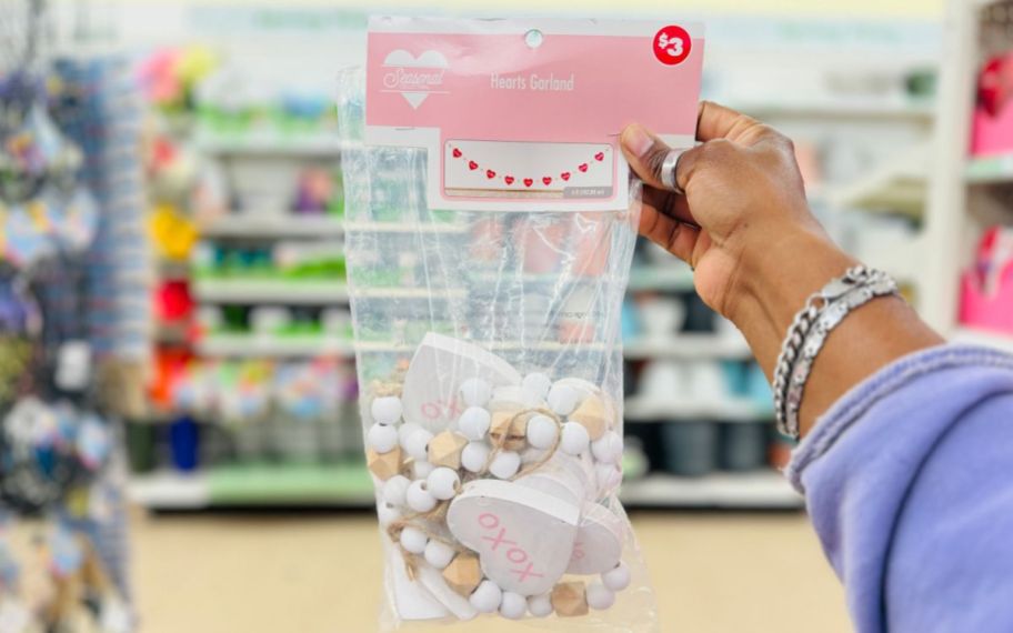 a womans hand a bag of wooden heart garland