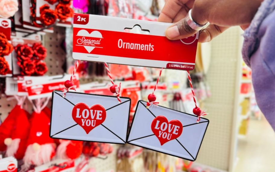 a womans hand holding a bag of valentines love letter ornaments