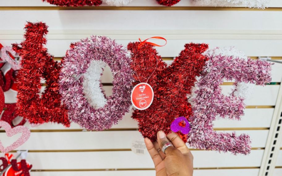 a womans hand holding a love tinsel decor