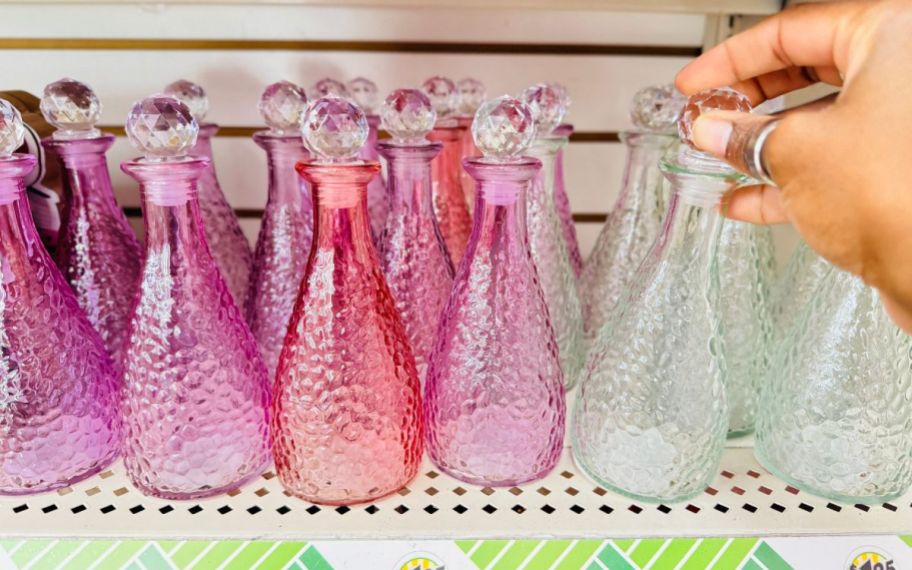 a womans hand grabbing a decorative bottle from a store shelf