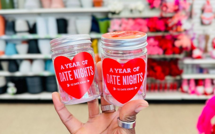 a womans hand holding two jars of date night ideas