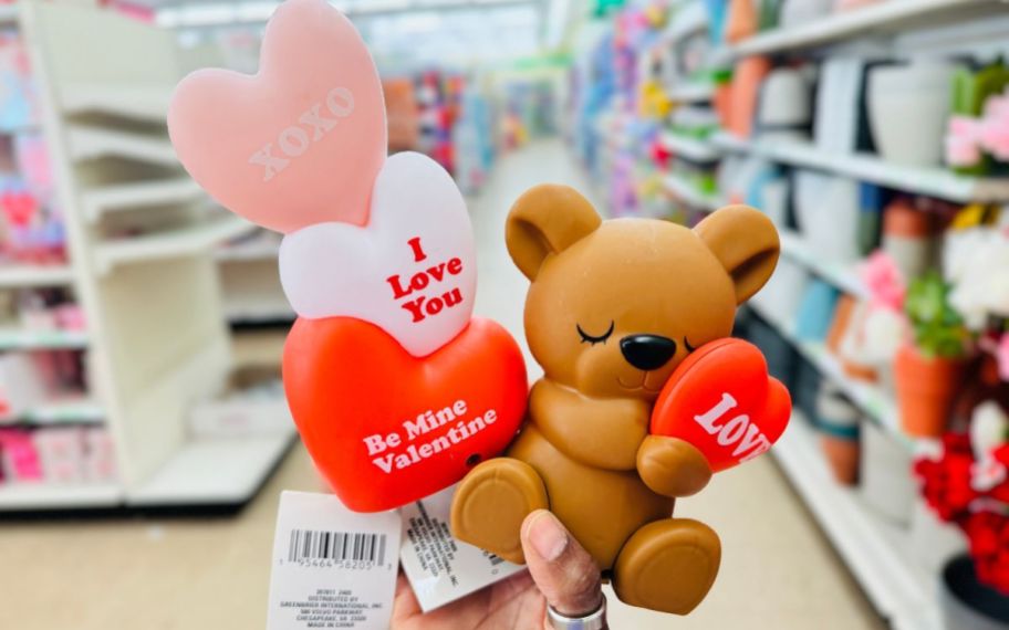 a womans hand holding two plastic table top decor items