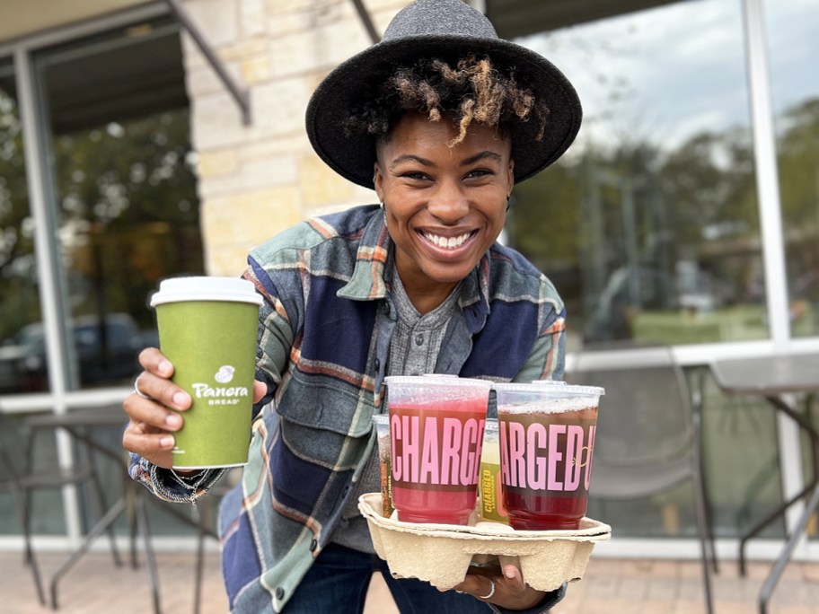 woman holding a coffee and tray of drinks from panera