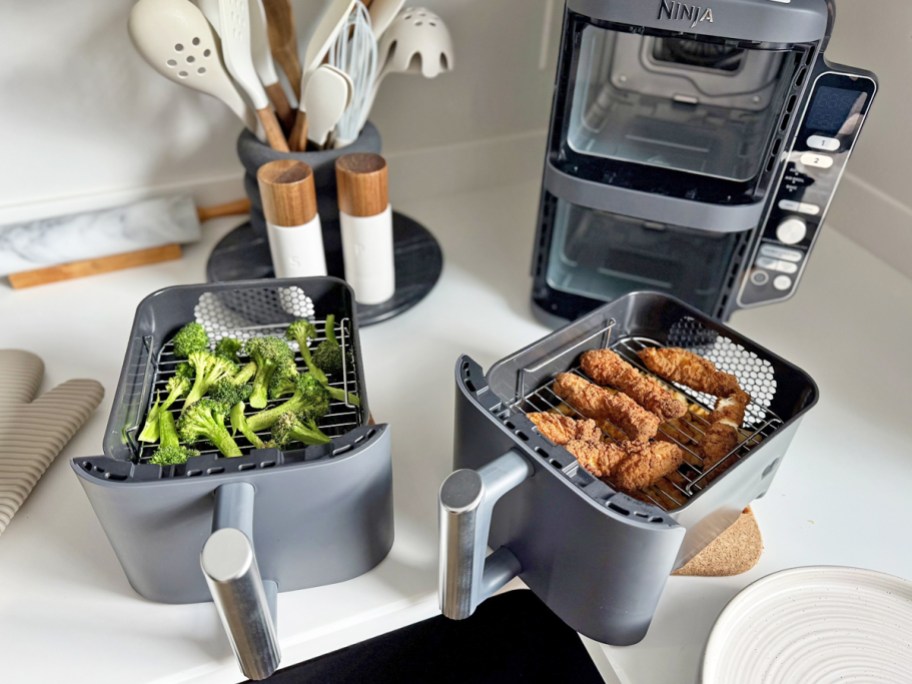 Ninja DoubleStack Air Fryer baskets on counter with broccoli and chicken strips inside