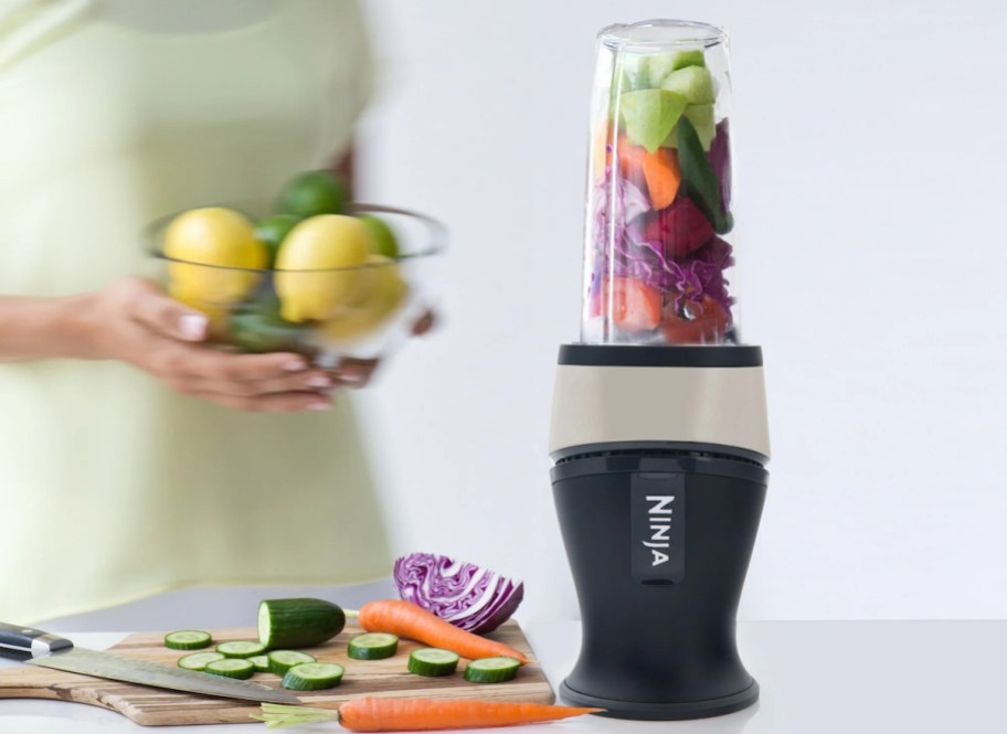 ninja fit personal blender on counter with woman holding clear bowl of lemons and limes