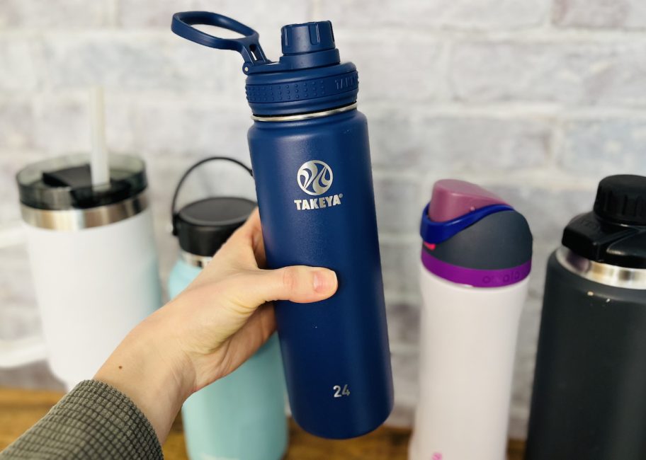 Hand holding a navy blue takeya water bottle