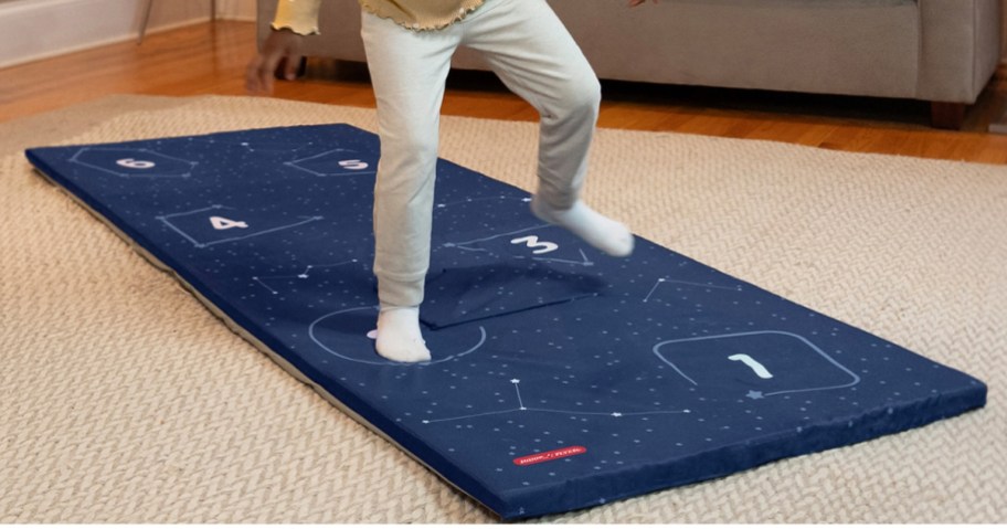 little girl jumping on a blue play mat in a living room