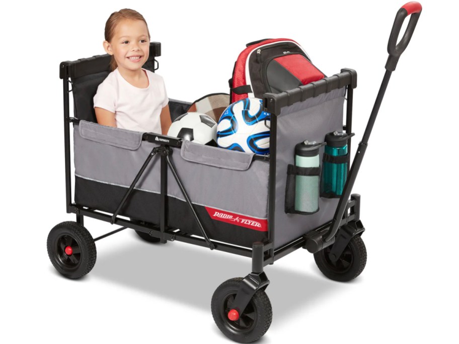 gray radio flyer wagon with child sitting in it with soccer equipment