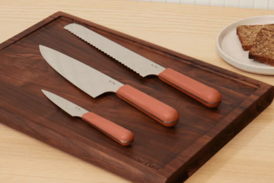 three terracotta colored knives on cutting board 