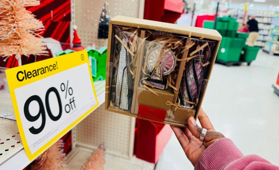 a woman holding an ornament set up to a clearance sign