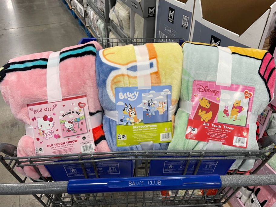 A Sam's Club cart with 3 licensed character valentine's day throw blankets in the front basket